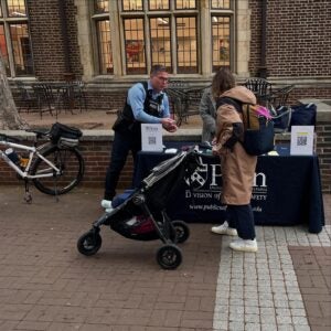 An Officer handing out pamphlets to a person pushing a stroller
