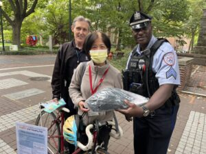 A photo of an officer handing a helmet to a community member