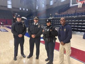 four officers stand on the sidelines of the basketball court