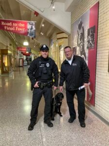 Two officers pose with K9 Officer Toby in the concourse of the Palestra