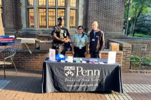 Three personnel from Public Safety pose behind a table with giveaways and informational signage