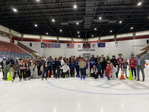 Large group photo of participants posing on the ice at the Penn Ice Rink 