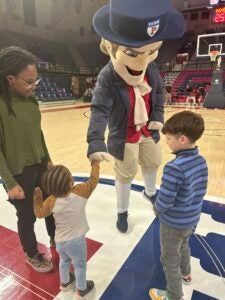 The Quaker mascot fist-bumps with a small child