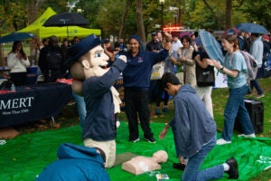 The Penn Quaker, a mascot, performs hands-only CPR on a test unit.